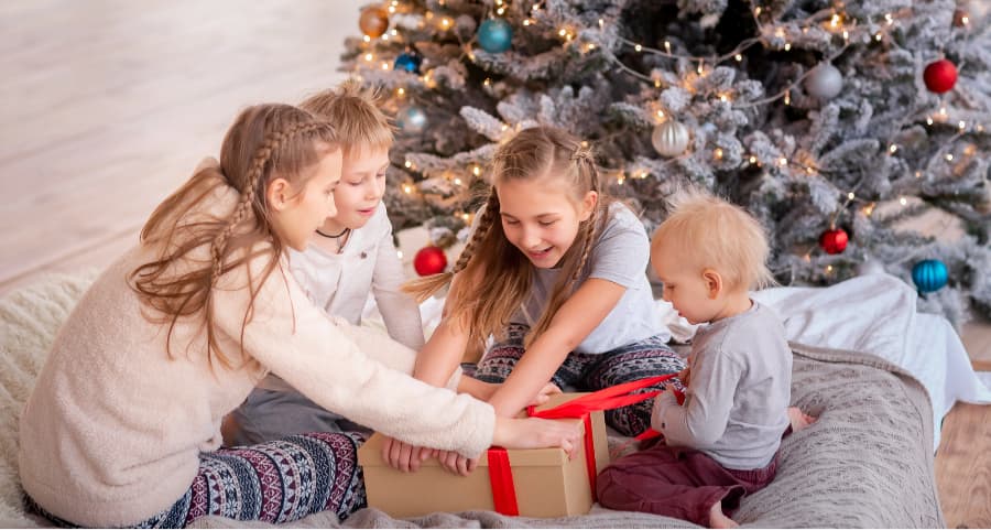 Kids opening a gift near a Christmas tree.